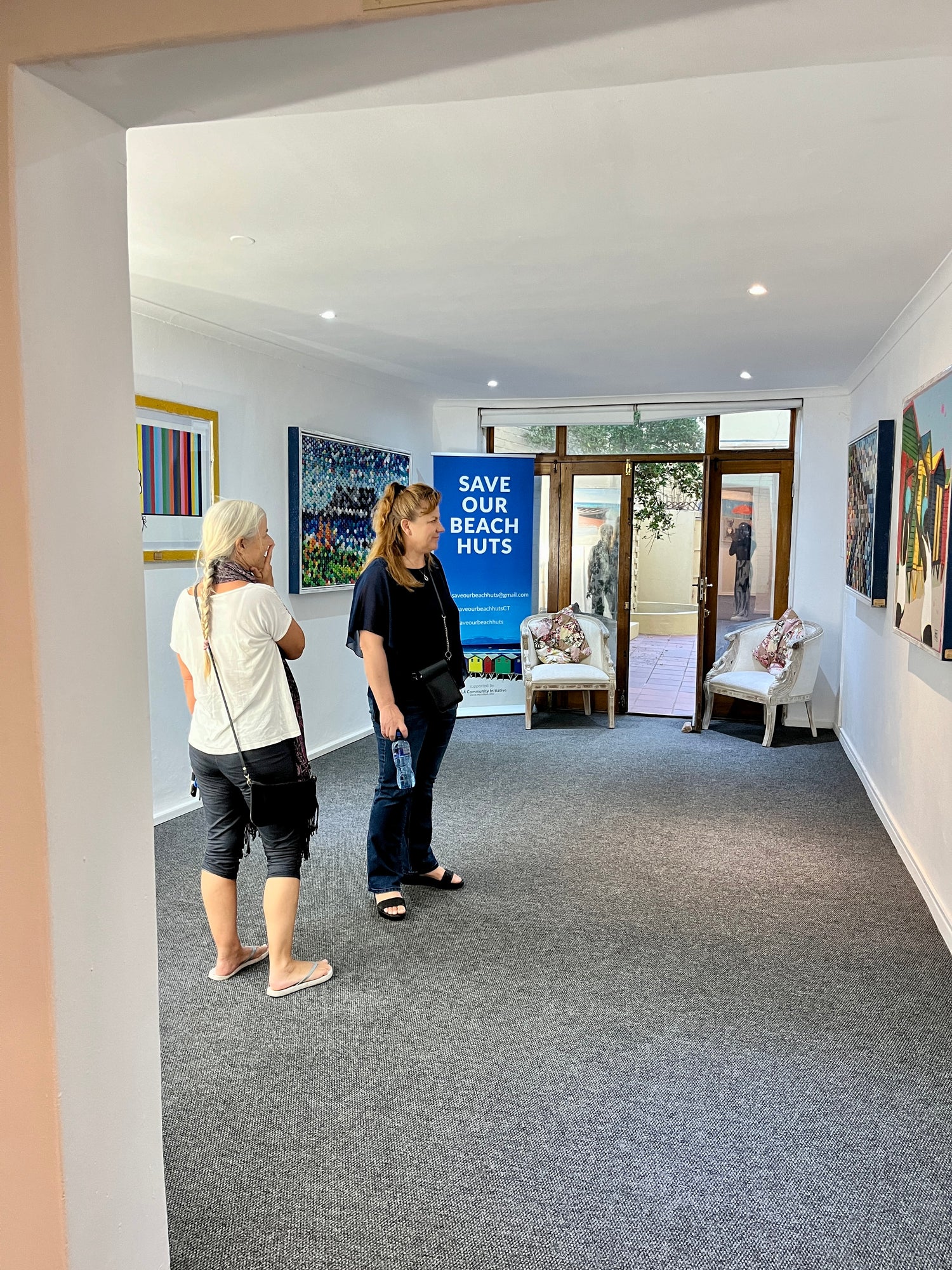 Two people viewing art at an art show in muizenberg