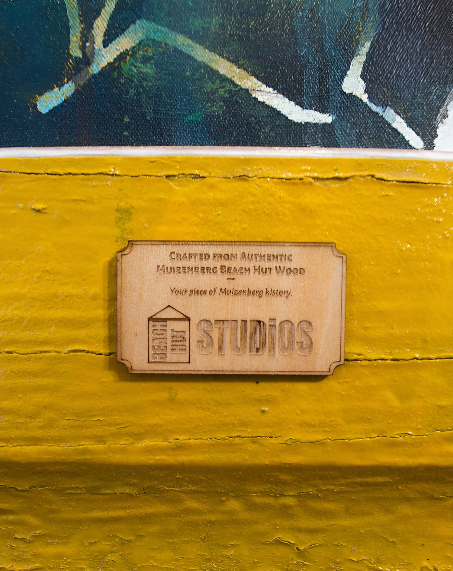 A beach hut studios badge on a frame made from retired beach hut wood